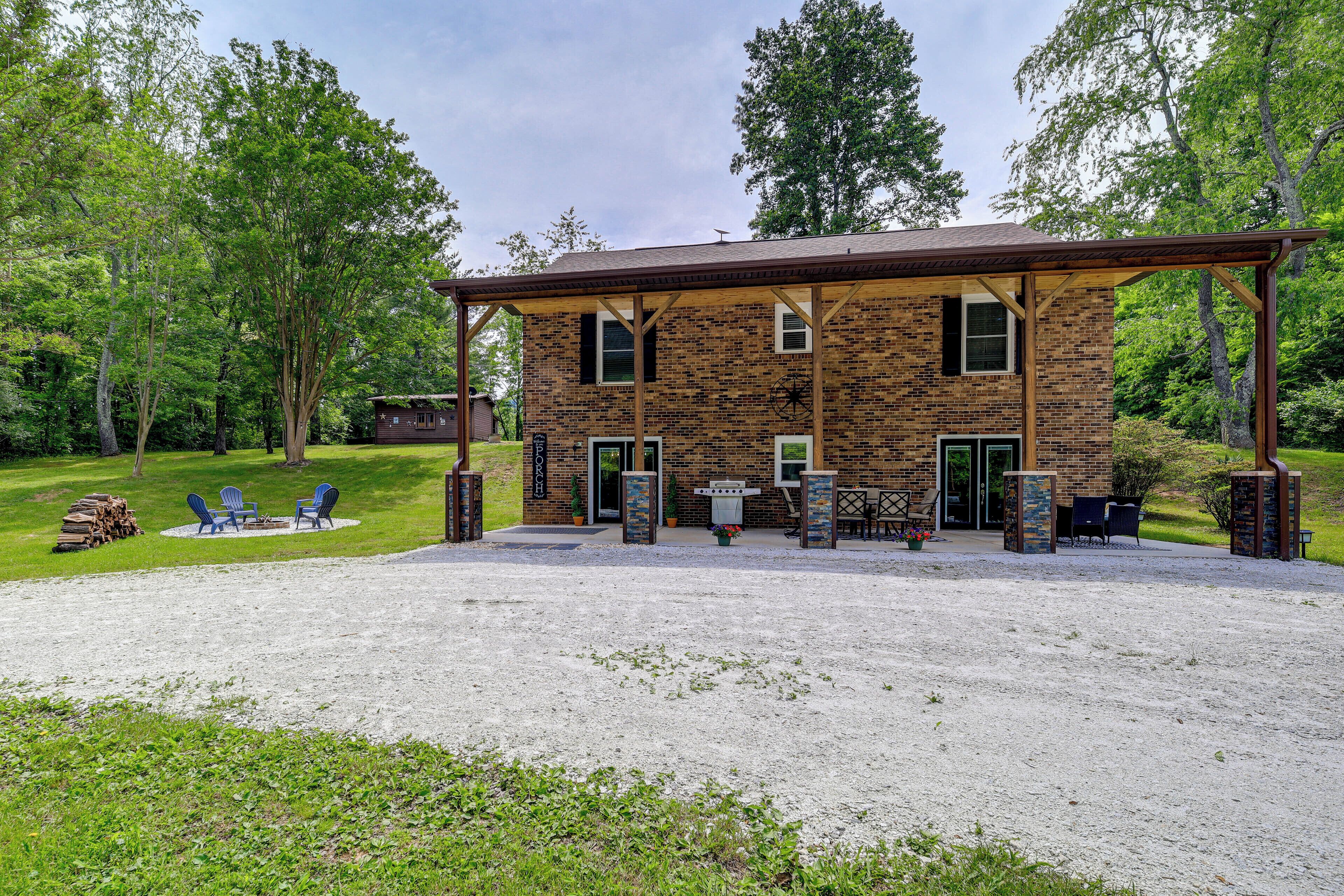 Ein zweistöckiges Backsteinhaus mit überdachter Terrasse, Außenbereich mit Sitzgelegenheiten und Grill.