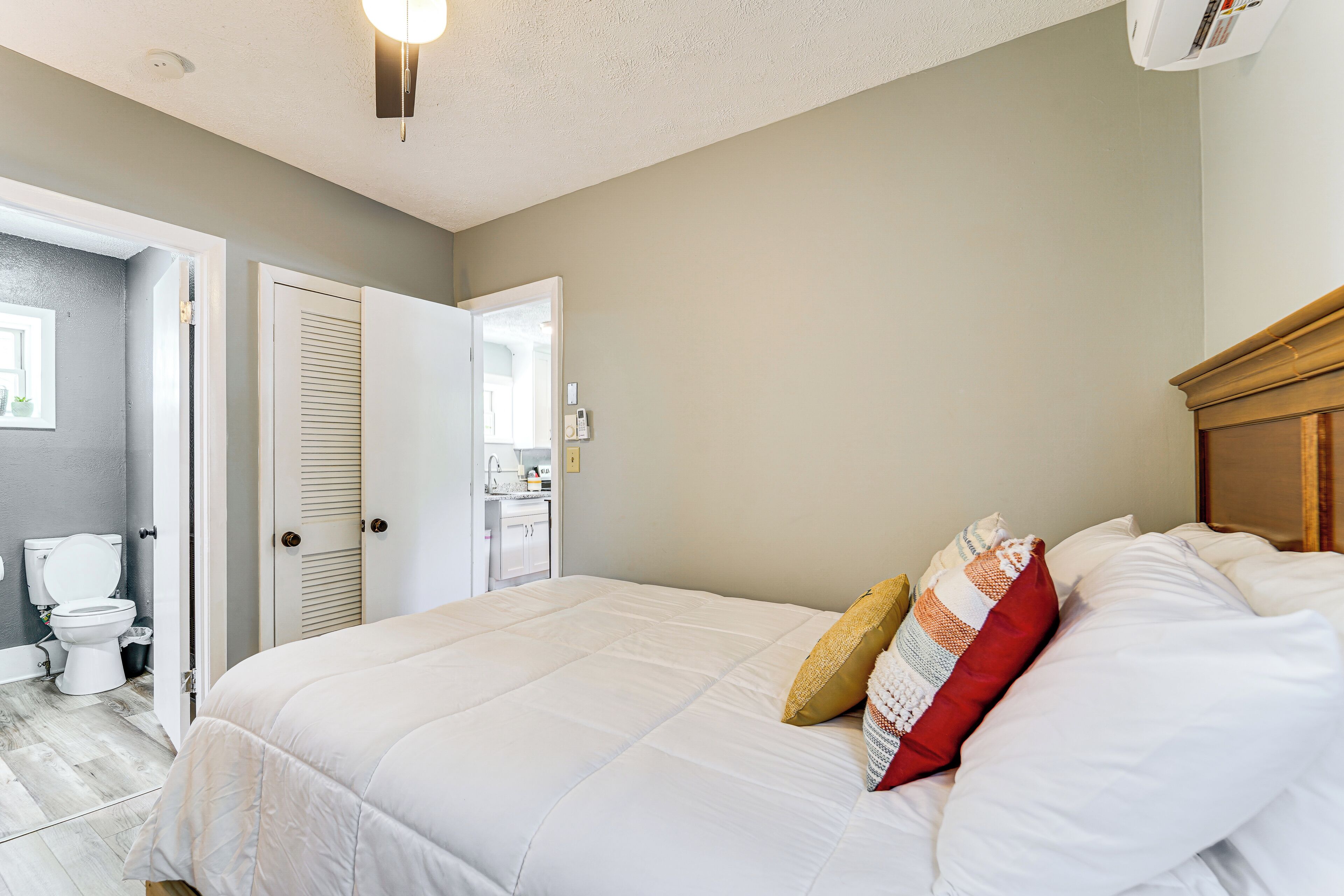A bedroom with a large bed, a wooden headboard, and a door leading to a bathroom.