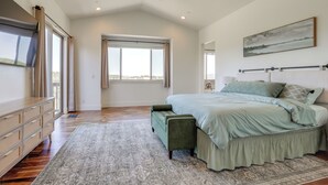 Una camera da letto con un letto grande, un ventilatore a soffitto, una TV e una finestra con tende.