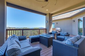 A covered outdoor seating area with wicker furniture and a view of the landscape.