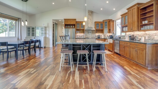 Un'ampia cucina con mobili in legno, una grande isola con sgabelli e una ventola a soffitto.