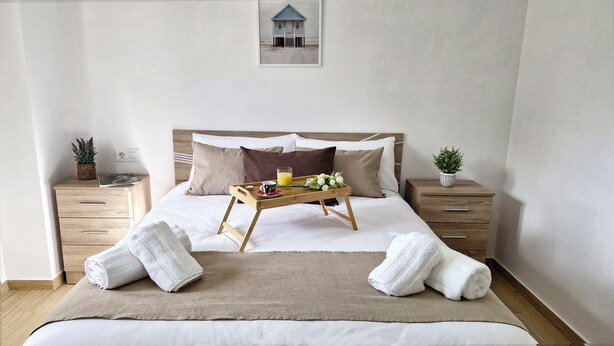 A neatly made bed with a tray of breakfast items, two bedside tables with plants, and a framed picture on the wall. - COMPLETE APARTMENT WITH TERRACE (Mondariz)