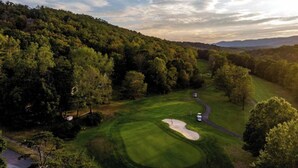 Un campo de golf con un fairway bien cuidado, búnkeres de arena y un club house.