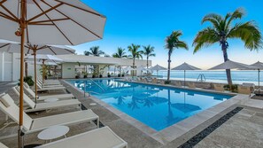 A pool area with lounge chairs and umbrellas, a clear view of the ocean, and palm trees. - Panoramic Hot Tub Oceanview Luxury 4BR Penthouse (Puerto Vallarta)