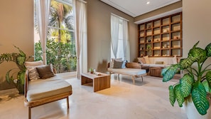 Uma sala de estar moderna com sofá, mesa de centro e grandes janelas com vista para um jardim.