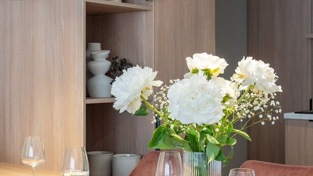 A dining table set with plates, glasses, and cutlery, with a vase of flowers and a hanging light fixture. - Spacious 3BR by Cismigiu Gardens Calea Victoriei (Bucharest)