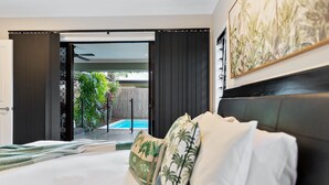 A hotel room with a bed, a view of a swimming pool, and a door leading outside. - Modere - Pool Entertainer Child Pet (Cairns)