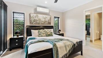 A modern bedroom with a large bed, bedside tables, and a ceiling fan.