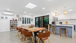 A modern kitchen with a central island, white cabinetry, and pendant lighting. - Curlews Nest - Pool BBQ and Beach (Cairns)