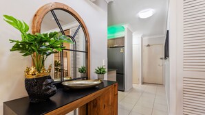 Une cuisine moderne avec une console en bois, un grand miroir et un réfrigérateur.