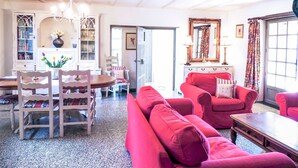 A spacious living room with a dining area, a red sofa, and a chandelier. - L'Ecurie - The original farmer's cottage (Larzac)