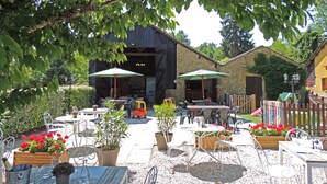 An outdoor patio area with tables and chairs, surrounded by greenery and a stone building. - La Grange - sleeps 6 guests  in 3 bedrooms (Larzac)