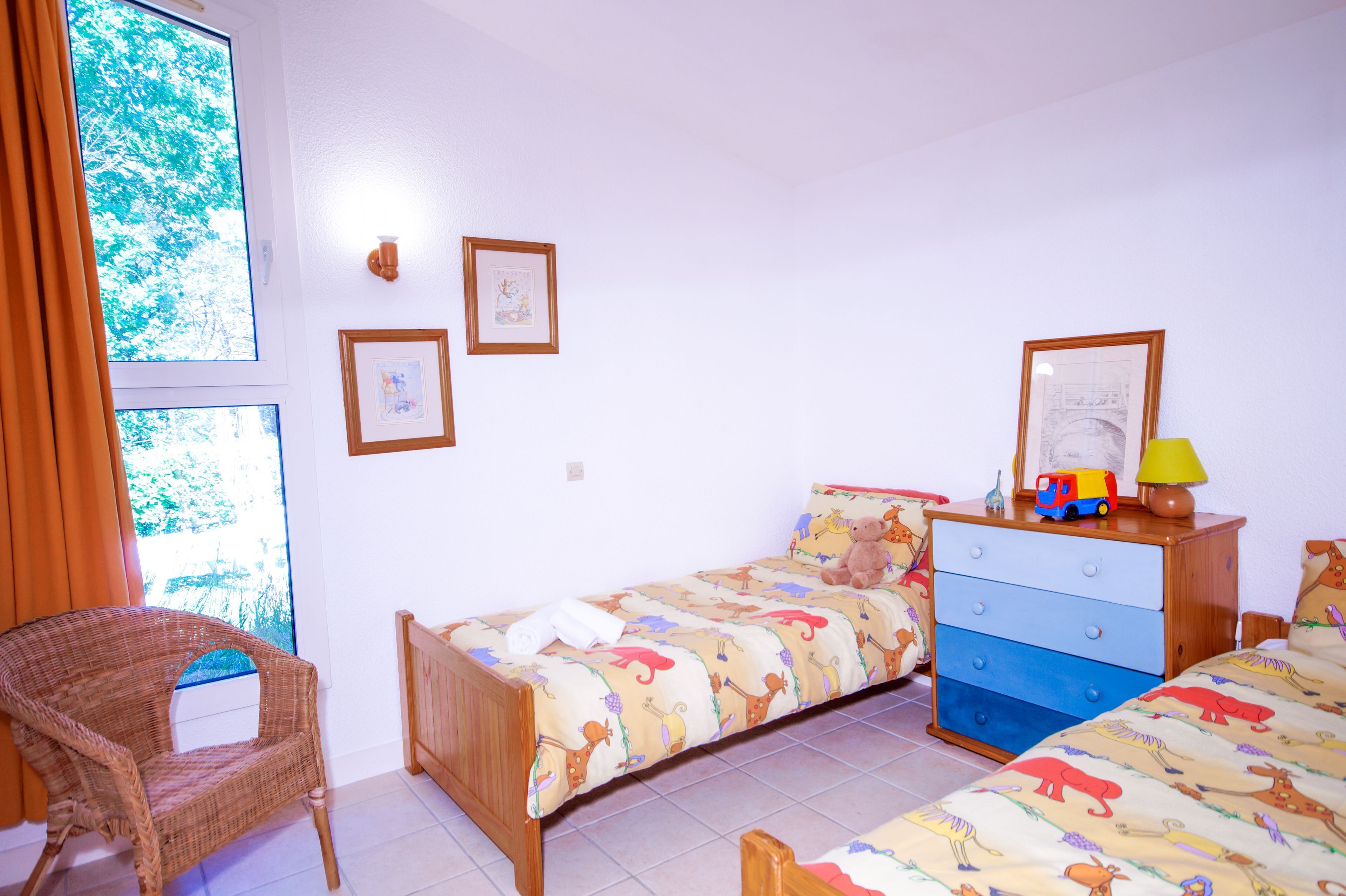 Quarto com cama, penteadeira, cadeira e duas quadros pendurados na parede.