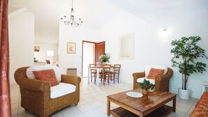 Una sala de estar con muebles de mimbre, una mesa de centro de madera y un comedor con una mesa y sillas.