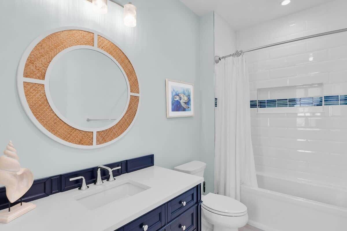A bathroom with a round mirror, a white sink, a toilet, and a shower curtain.