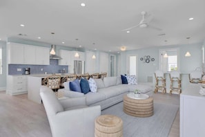 A spacious living room with a large sofa, a coffee table, and a dining area with chairs.