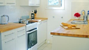 Eine moderne Küche mit weißen Schränken, einer Holz Arbeitsplatte, einem eingebauten Backofen, einem Fenster mit Aussicht und einem Spülbecken mit Armatur.