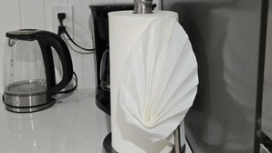 Una cocina con cafetera, dispensador de toallas de papel y lavavajillas.