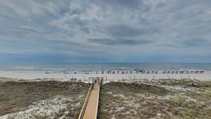 A beach with a wooden boardwalk leading to the water, sandy beach, and a cloudy sky. - Ocean Breeze West 301, 3BD/2BA, Community Pool + Private Beach (Perdido Key)
