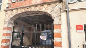 A building with a black gate, a sign indicating a tourist residence, and a sign for a reserved parking area.