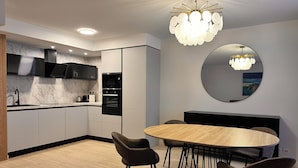 A modern kitchen with a round dining table, black chairs, and a large mirror.