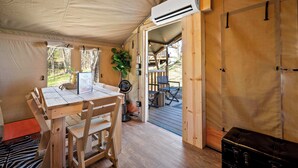Un intérieur en bois comprenant une table à manger, des chaises, un appareil de climatisation et une valise.