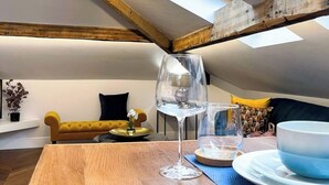 Een eetgedeelte met een houten tafel, een wijnglas en een schaal op een blauwe placemat.