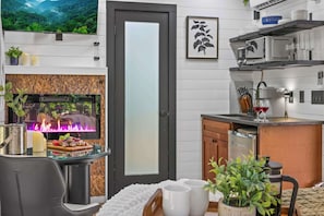 A modern kitchen with a flat-screen TV, a fireplace, and a dining area with a table set for two.