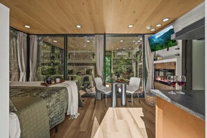 Una habitación moderna con cama, una mesa de comedor con sillas, televisión y chimenea.