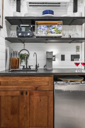 A modern kitchen with a built-in oven, coffee maker, and a sink.