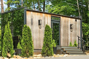 Une cabane en bois avec une porte en métal, des marches et deux lampes de style lanterne.