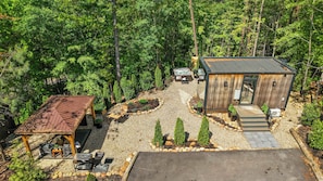 A cabin with a hot tub, a covered outdoor seating area, and a gravel driveway.