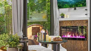 A cozy room with a fireplace, a small table with candles, and a view of the outdoors.