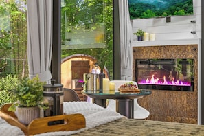 A cozy room with a fireplace, a small table with candles, and a view of the outdoors.