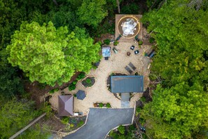 A circular outdoor seating area with a hot tub, surrounded by trees and a gravel path. - Villa Sol-Mirror Cabin-Private-Hot Tub-FirePit-Luxury (Sevierville)