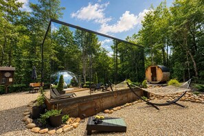 A rustic outdoor area with a hammock, a wooden barrel, and a dome-shaped structure. - Villa Luna-Mirror Cabin-Luxury-Hot Tub-FirePit-Secluded (Sevierville)