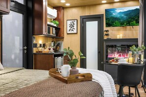 Una habitación moderna con una cama, un comedor con mesa y sillas, una cocina con microondas y una chimenea.