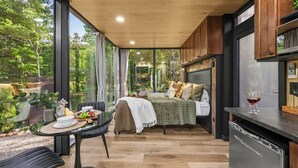 Un dormitorio moderno con cama, una mesa de comedor con sillas y una zona de cocina con lavavajillas.