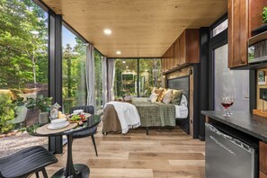 Un dormitorio moderno con cama, una mesa de comedor con sillas y una zona de cocina con lavavajillas.