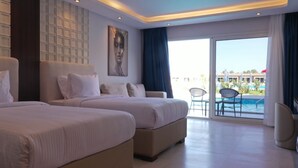 A hotel room with two beds, a large window with a view of a pool and outdoor area, and a ceiling with recessed lighting. - Rewaya Majestic Resort (Hurghada)