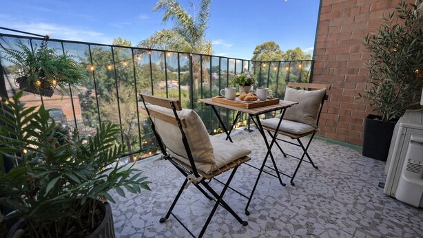 Eine Terrasse im Freien mit einem Tisch, zwei Stühlen, einem Blumentopf und einer Backsteinmauer.