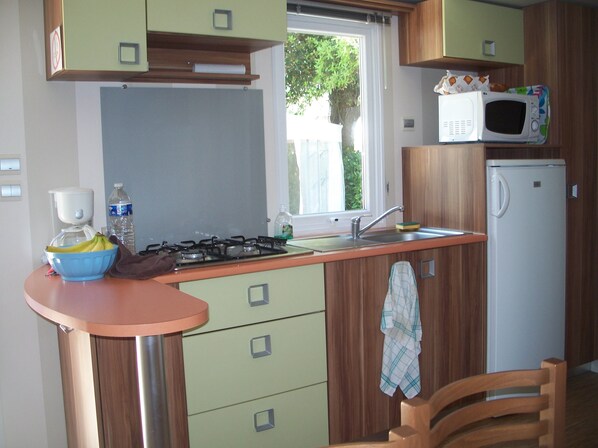 A compact kitchen with a gas stove, a microwave, and a refrigerator.