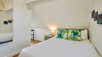 A hotel room with a bed, a nightstand, a chair, and a small table.