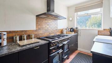 A kitchen with a gas stove, oven, and a window with a view of trees.