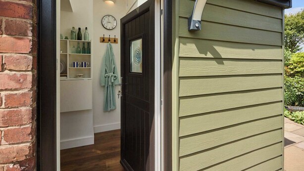 A bathroom with a wooden door, a clock, and a towel rack. - Host & Stay | Garden Studio (Hartlebury)