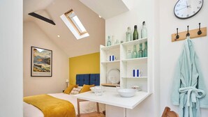 A modern bedroom with a bed, a desk, and a shelf with bottles. - Host & Stay | Garden Studio (Hartlebury)