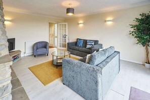 A living room with a stone fireplace, a grey sofa set, a coffee table, and a potted plant. - Host & Stay | Saltdean Sea View (Saltdean)