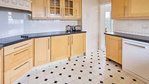 A kitchen with wooden cabinets, a black countertop, and a tiled floor with a black and white pattern.
