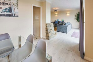 A modern interior with a seating area, a stone accent wall, and a view of the outdoors. - Host & Stay | Saltdean Sea View (Saltdean)