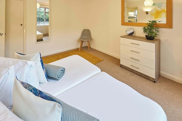Una habitación de hotel con cama, cómoda, silla y un espejo grande.